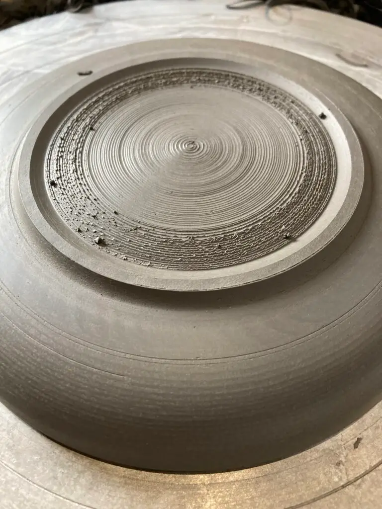 Avec sa mirette, Claire définit les lignes de la pièce créée. La terre est à consistance cuir.